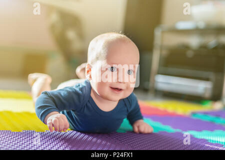 Portrait von niedlichen kaukasische Baby boy Kriechen auf weiche, matte im Innenbereich. Adorable Kind Spaß machen, die ersten Schritte auf dem Boden im Kindergarten. Bac Stockfoto