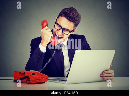 Wütend Geschäftsmann Calling Service mit einem Laptop Ausfall schreiend auf dem Telefon Stockfoto
