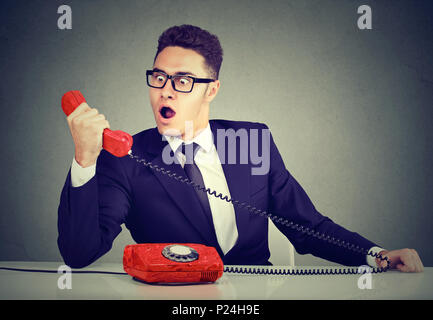 Young Business Mann empfängt fehlerhafte Nachrichten auf dem Telefon am Schreibtisch sitzt in seinem Büro Schockiert Stockfoto