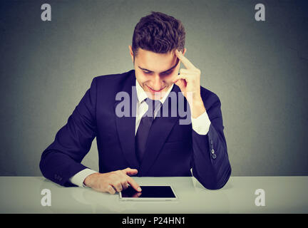 Schöne elegante glücklicher Mann in Anzug stöbern Tablet zuversichtlich suchen und entspannt. Stockfoto