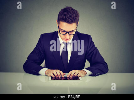 Hübscher junger Geschäftsmann mit einem Tablet Computer, während am Schreibtisch arbeiten Stockfoto