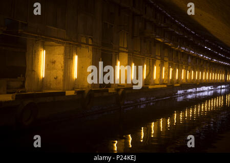 Die künstlichen Tunnel mit der Anlegestelle, Reifen vor langer Zeit ohne Arbeit geworfen. mit künstlicher Beleuchtung. Stockfoto