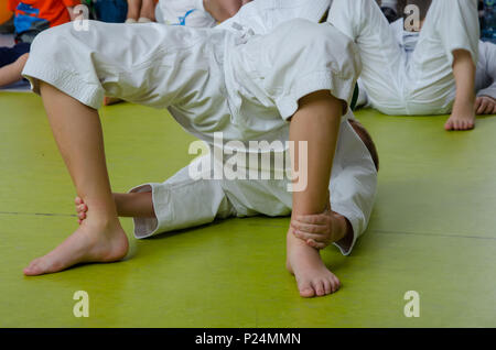 Ein Junge in den Kimono üben Karate auf dem Boden in der Turnhalle Stockfoto