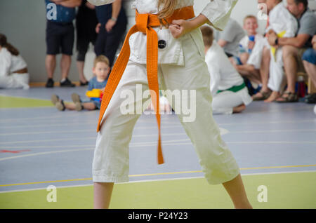 Karate Wettbewerb. Ein Mädchen im Kimono mit orangen Gürtel. kein Gesicht. die Hand ist in der Faust komprimiert Stockfoto