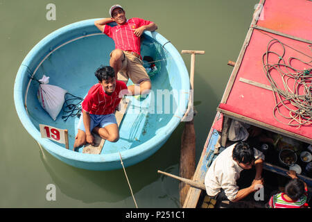 Phan Thiet, Vietnam - Januar 2014: Zwei glücklich lächelnde junge Männer in traditionellen Warenkorb Boot auf dem Fluss in Phan Thiet, Vietnam Stockfoto