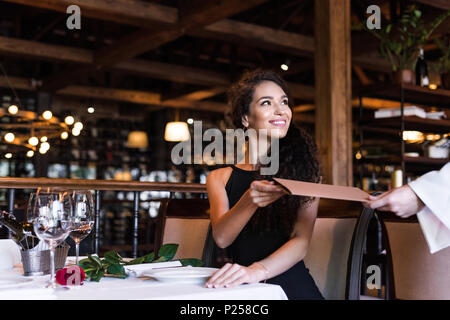 Junge schöne Frau unter Menü von Kellner im Restaurant Stockfoto