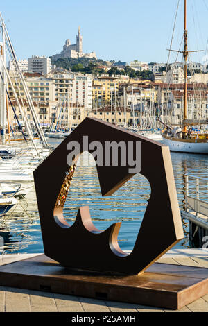 Das M Logo der Stadt Marseille auf dem Alten Hafen mit Liebe Schlösser, Yachten in der Marina vor Anker und der Basilika Notre-Dame de la Garde auf dem Hügel Stockfoto