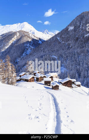 Eine Spur im Schnee führt zu den traditionellen Hütten in Blatten. Zermatt, Wallis/Wallis, Schweiz. Stockfoto