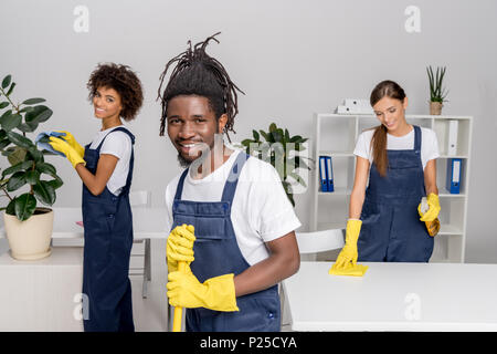 Multiethnische Gruppe professioneller Reiniger in Gummihandschuhe Lächeln auf die Kamera, während arbeiten zusammen Stockfoto