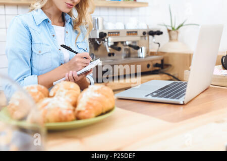 7/8 Schuß von cafe Eigentümer Notizen und mit Laptop Stockfoto