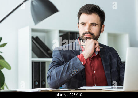 Nachdenkliche junge Unternehmer am Arbeitsplatz im Büro Stockfoto
