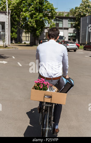 Ansicht der Rückseite des manager Reiten auf dem Fahrrad mit Box von persönlichen Sachen auf Trunk Stockfoto