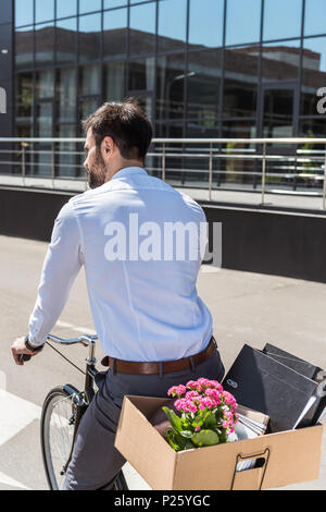 Ansicht der Rückseite des jungen Manager reiten auf dem Fahrrad mit Box für Amtsleitung Stockfoto