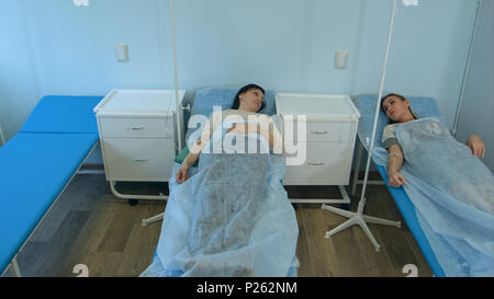 Zwei weibliche Patienten liegend im Krankenhaus Betten auf Tropfen sprechen Stockfoto