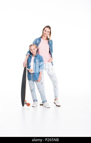 Kleine Tochter und ihre Mutter posiert mit einem Longboard, isoliert auf weißem Stockfoto