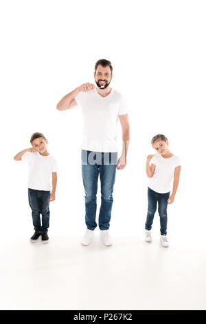 Junger Vater und Kinder auf Kamera beim Zähneputzen zusammen isoliert auf weißem Stockfoto