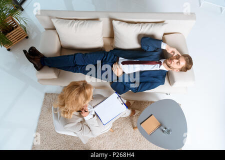 Draufsicht des Psychologen arbeiten mit jungen Geschäftsmann auf der Couch liegend Stockfoto