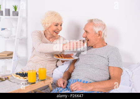 Gerne älteres Paar Frühstück im Bett zusammen zu Hause Stockfoto