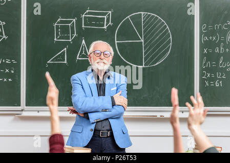 Graue Haare Professor an Studenten steigende Hände Stockfoto