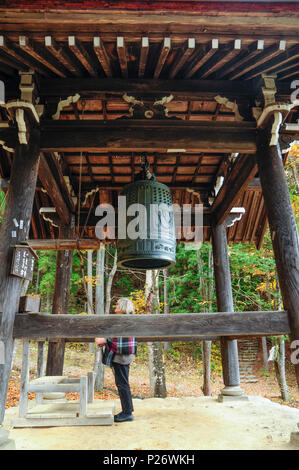 Eine weibliche ausländische Touristen die Erkundung der Glockenturm der ein Shinto Schrein im Hida-no-Sato Folk Village, Takayama, Japan Stockfoto