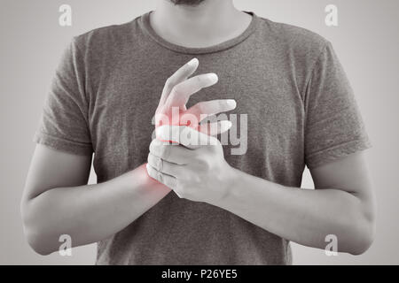 Asiatischer Mann mit Schmerzen im Handgelenk gegen grauen Hintergrund. Menschen mit chronischen Gelenk Rheuma. Körper & Gesundheit Konzept Stockfoto