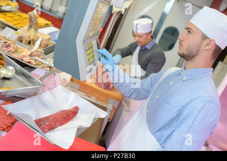 Metzger Lehrling mit einem Gewicht von Fleisch Stockfoto