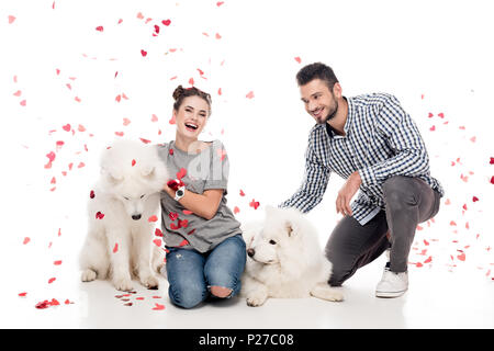 Paar mit Hunden unter fallenden Konfetti auf Weiß, Valentines Tag Konzept Stockfoto