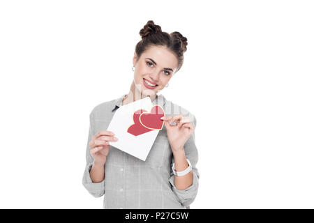 Lächelnde Mädchen Holding valentines Postkarte und Umschlag isoliert auf weißem Stockfoto