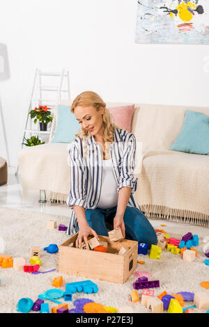 Schwangere Frau sammeln Kinder Spielzeug Stockfoto