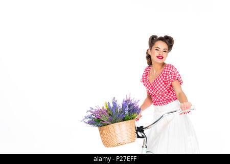 Attraktive Pin up Frau auf Fahrrad mit Korb mit Blumen isoliert auf weißem Stockfoto