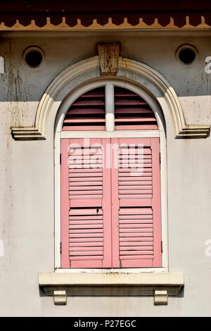 Vertikale Ansicht von traditionellen vintage Singapur shop Haus mit antiken rosa Fensterläden und Bogenfenster auf einer weißen Wand im historischen Little India Stockfoto