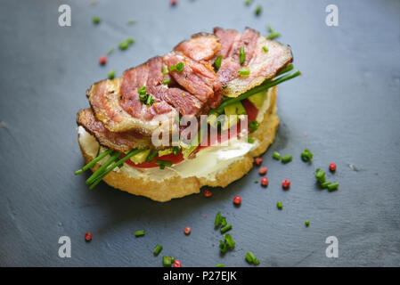 Ein schönes Sandwich mit Speck, Avocado und Zwiebeln auf dunklem Schiefer Fach. Stockfoto