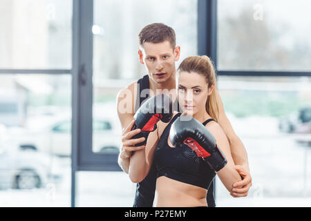 Männliche Trainer mit schönen weiblichen Boxer von der Kamera zusammen suchen Stockfoto