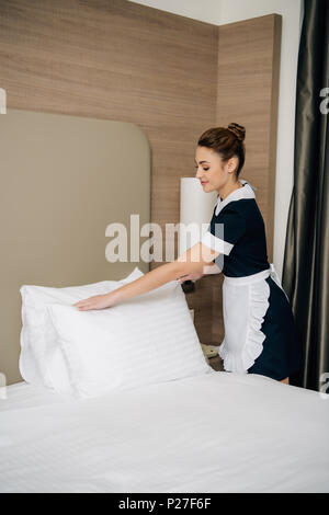 Junge glücklich Mädchen in Uniform, Bett im Hotel Suite Stockfoto