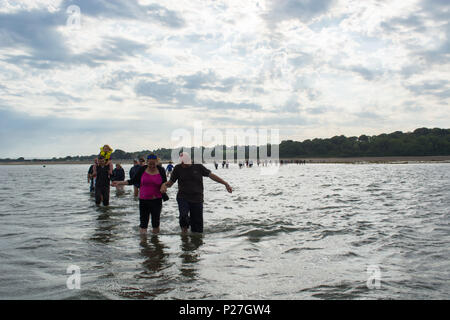 Die Teilnehmer am Bembriudge und St Helens jährlichen Fort gehen, waten, um das Fort in knietiefem Wasser. Stockfoto