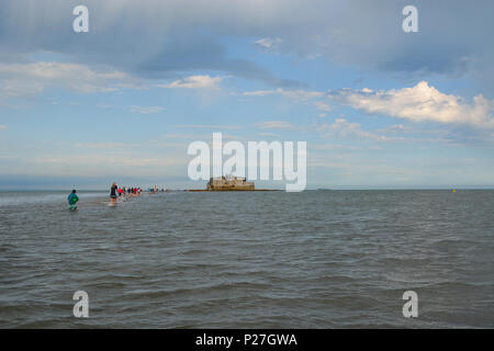 Die Teilnehmer am Bembriudge und St Helens jährlichen Fort gehen, waten, um das Fort in knietiefem Wasser. Stockfoto