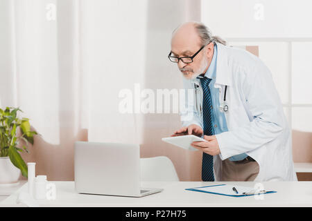 Portrait von leitenden Arzt im weißen Kittel mit Tablet in der Hand am Arbeitsplatz in der Klinik Stockfoto