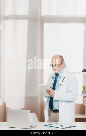 Portrait von leitenden Arzt im weißen Kittel mit Tablet in der Hand am Arbeitsplatz in der Klinik Stockfoto