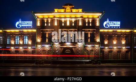 Tomsk, Russland - 10. Juni 2018: altes Backsteingebäude, das Gazprom, die von verschiedenen Laternen und Lampen in der Mitte der Stadt im Regen hervorgehoben bei Nacht Stockfoto