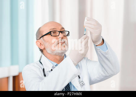 Portrait von leitenden Arzt in Brillen und medizinische Handschuhe halten Sie die Spritze in der Klinik Stockfoto