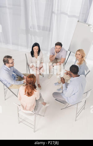 Ansicht von oben der multiethnischen im mittleren Alter Menschen sitzen auf Stühlen und Sprechen während der Gruppe Therapie Stockfoto