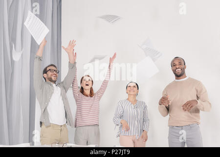 Aufgeregt multiethnischen im mittleren Alter Menschen werfen Papiere Stockfoto