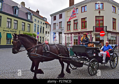 Touristen genießen die beliebte Kutsche Tour entlang der gepflasterten Straßen der Altstadt von Brügge und Oostende, Belgien Stockfoto