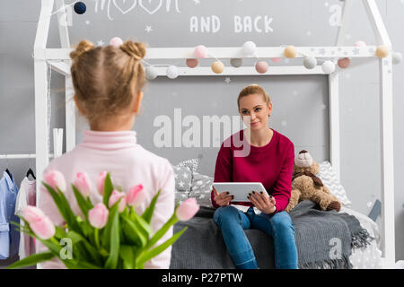 Tochter verstecken Tulpen Blumenstrauß für Mutter hinter zurück Stockfoto