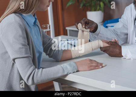 Zugeschnittenes Bild der afrikanischen amerikanischen Arzt bandagieren Patienten hand Stockfoto