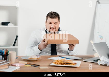 Übergewicht Geschäftsmann essen Pizza am Arbeitsplatz Stockfoto