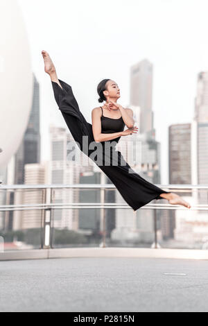 Schöne junge Mädchen tanzen in der Stadt, mit schwarzen, mit Hintergrund der Wolkenkratzer Stockfoto