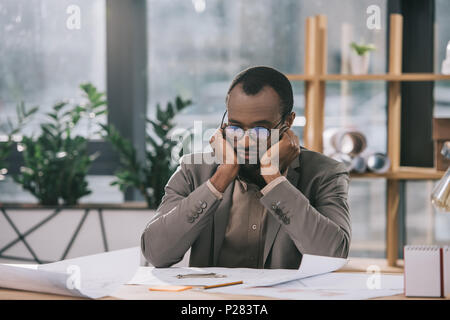 Nachdenklich african american Architect bei Blueprints im Büro suchen Stockfoto