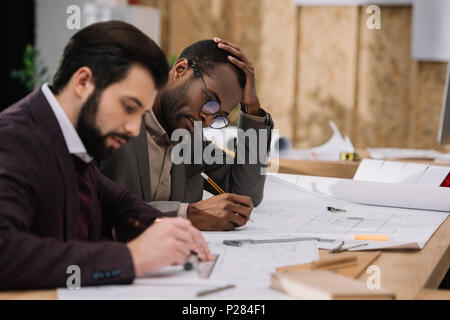 Konzentrierte junge Architekten zeichnen Baupläne zusammen Stockfoto