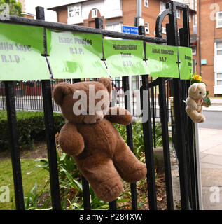 Anwohner, Kuscheltiere und die Namen der Opfer auf grüne Banner in Erinnerung an die 72 Menschen, die ihr Leben in der Grenfell Turm Brand verloren. Stockfoto